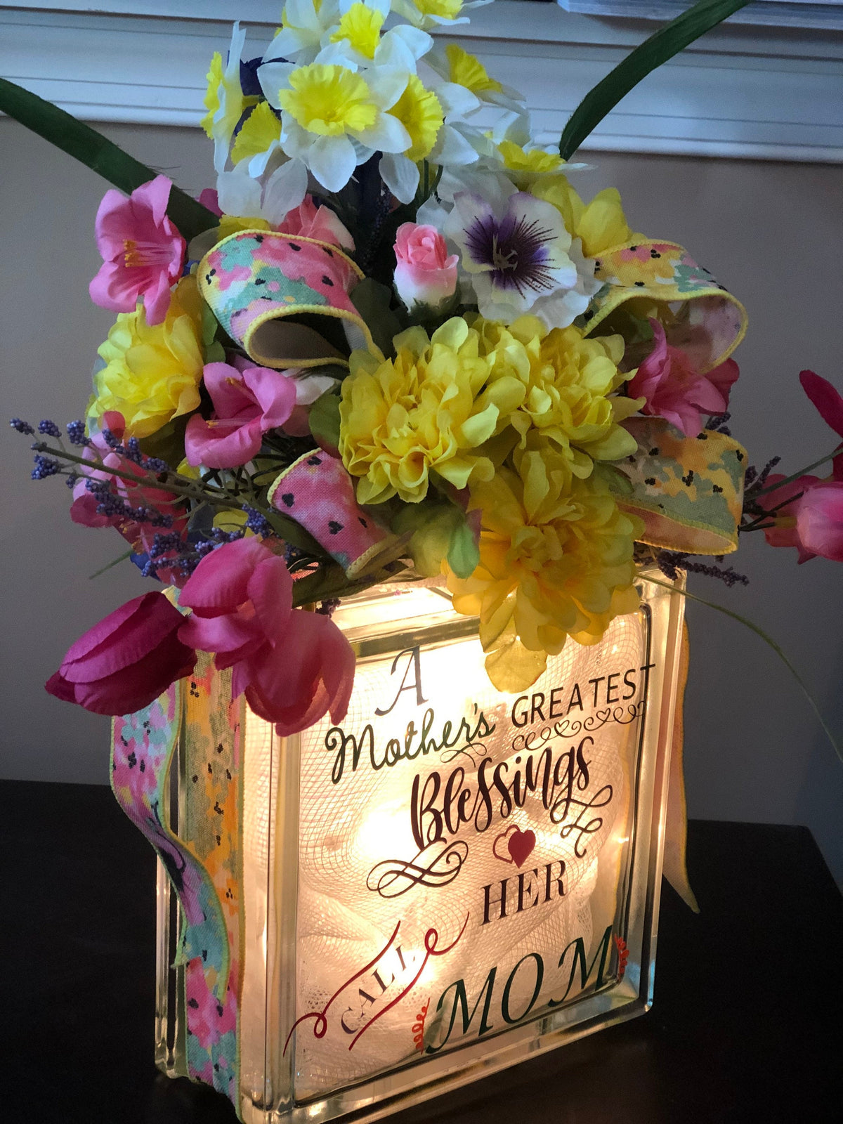 Mother's Day glass block lit up beneath a bright spring floral arrangement